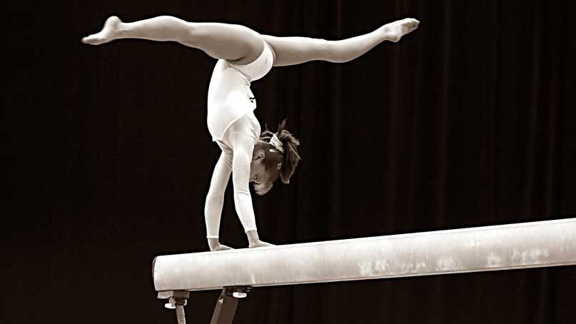 gymnast upside down on a balance beam