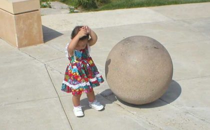small child next to a large stone ball
