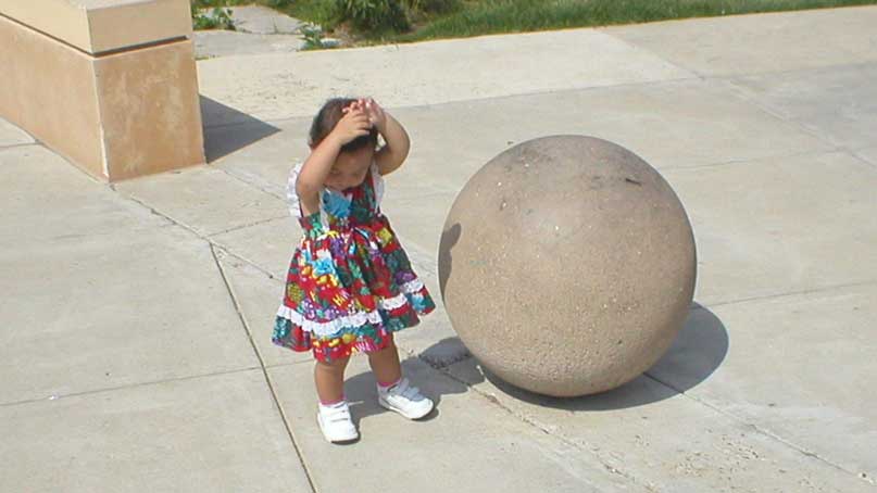 small child next to a large stone ball