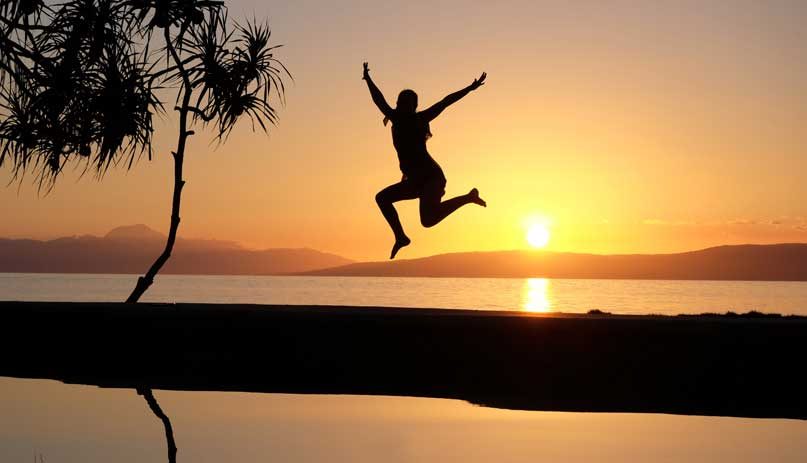 silhouette of person jumping on beach in front of sunset