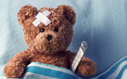 Teddy bear in a blanket with thermometer and bruise on head