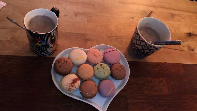 plate of macrarons with mugs of hot chocolate