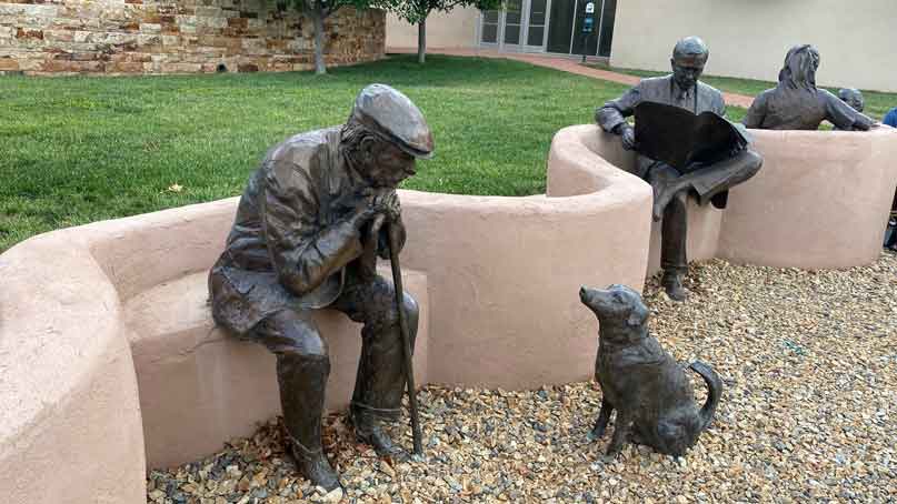 sculpture of an older man interacting with a small dog