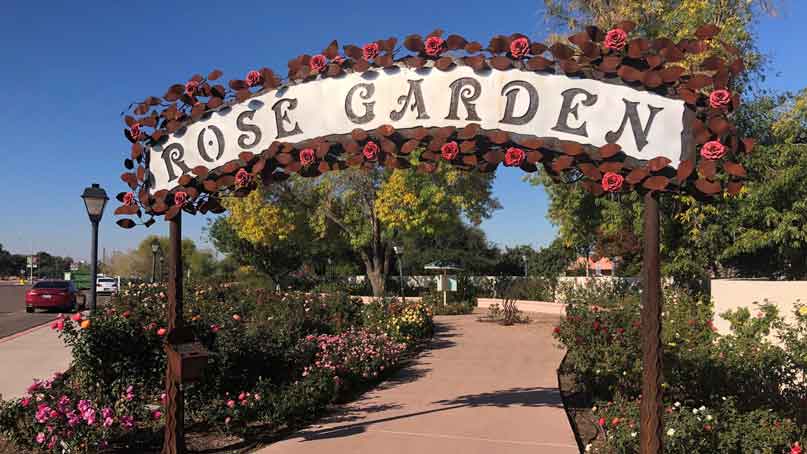 sign that says rose garden, adorned with roses