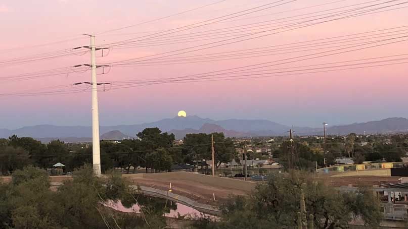 moon emerging from behind mountain