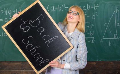 woman teacher holding blackboard that says back to school