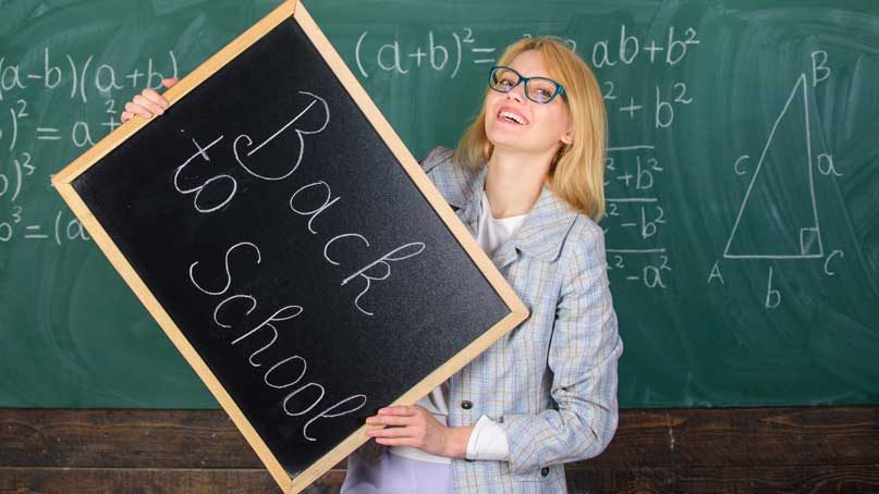 woman teacher holding blackboard that says back to school