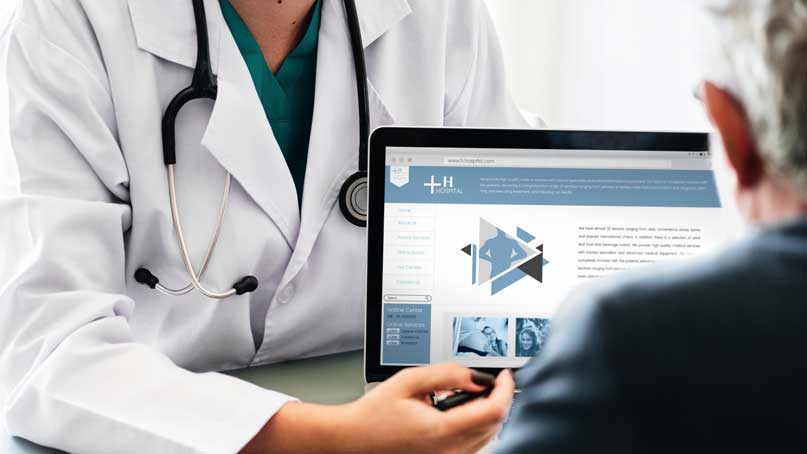 doctor speaking to elder person in front of computer