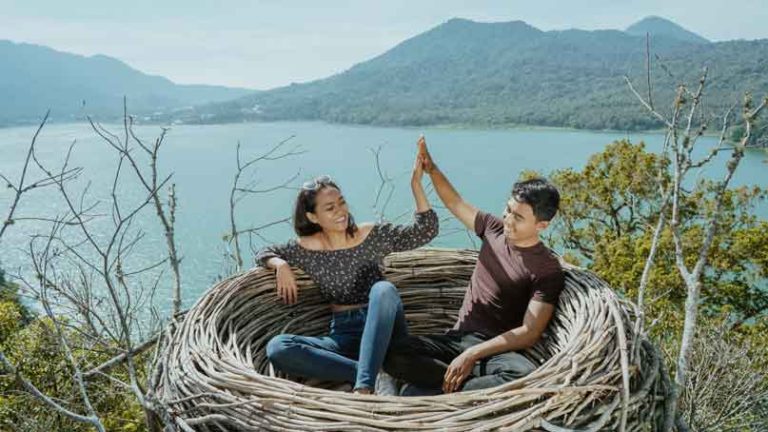 Couple sitting inside a nest overlooking a lake