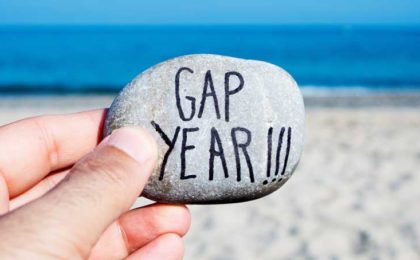 Hand holding a stone at the beach with the words Gap Year on it