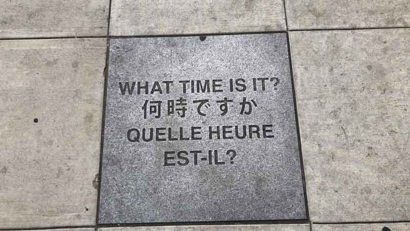 sidewalk plaque that says 'what time is it?'