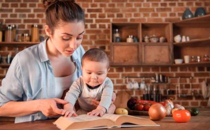 mother and child reading book in kitchen