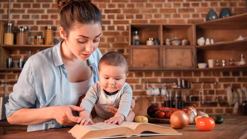 mother and child reading book in kitchen