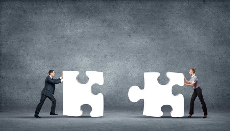 Two people pushing large puzzle pieces together