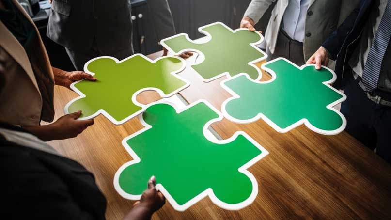 four people holding four large puzzle pieces