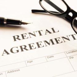 Paper that says Rental Agreement, with a pen and glasses laying on top