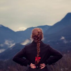 woman with hands behind back looking at mountains in the distance