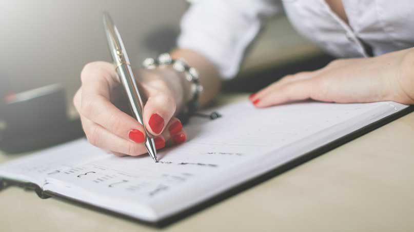 Notepad and hand of woman writing on it