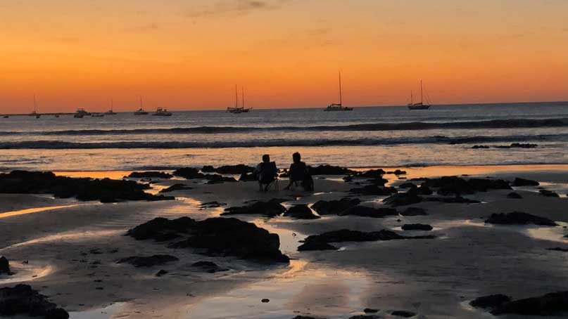 Couple watching sunset in Tamarindo from their beach chairs