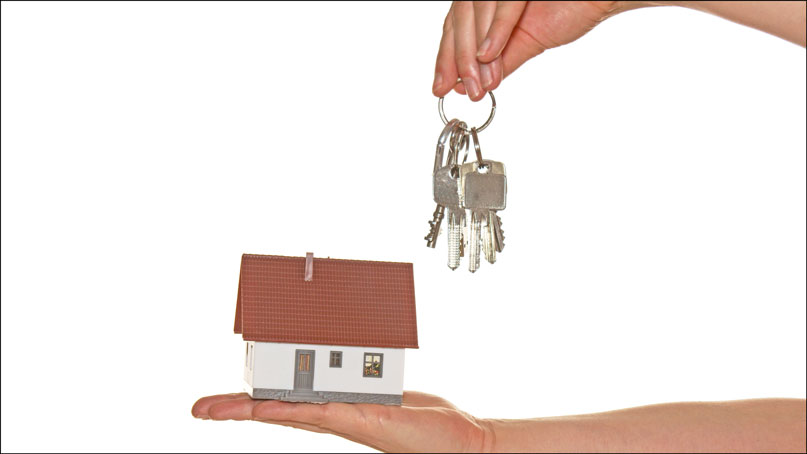 hand holding out a model of a house in one hand and keys in the other hand