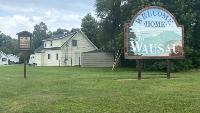 Lawn with house in background, and sign that says Welcome to Wausau