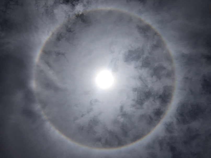 sun behind clouds with a halo around it